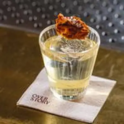 Terroir Old Fashioned in ornate rocks glass with honeycomb on top, on Overstory cocktail napkin