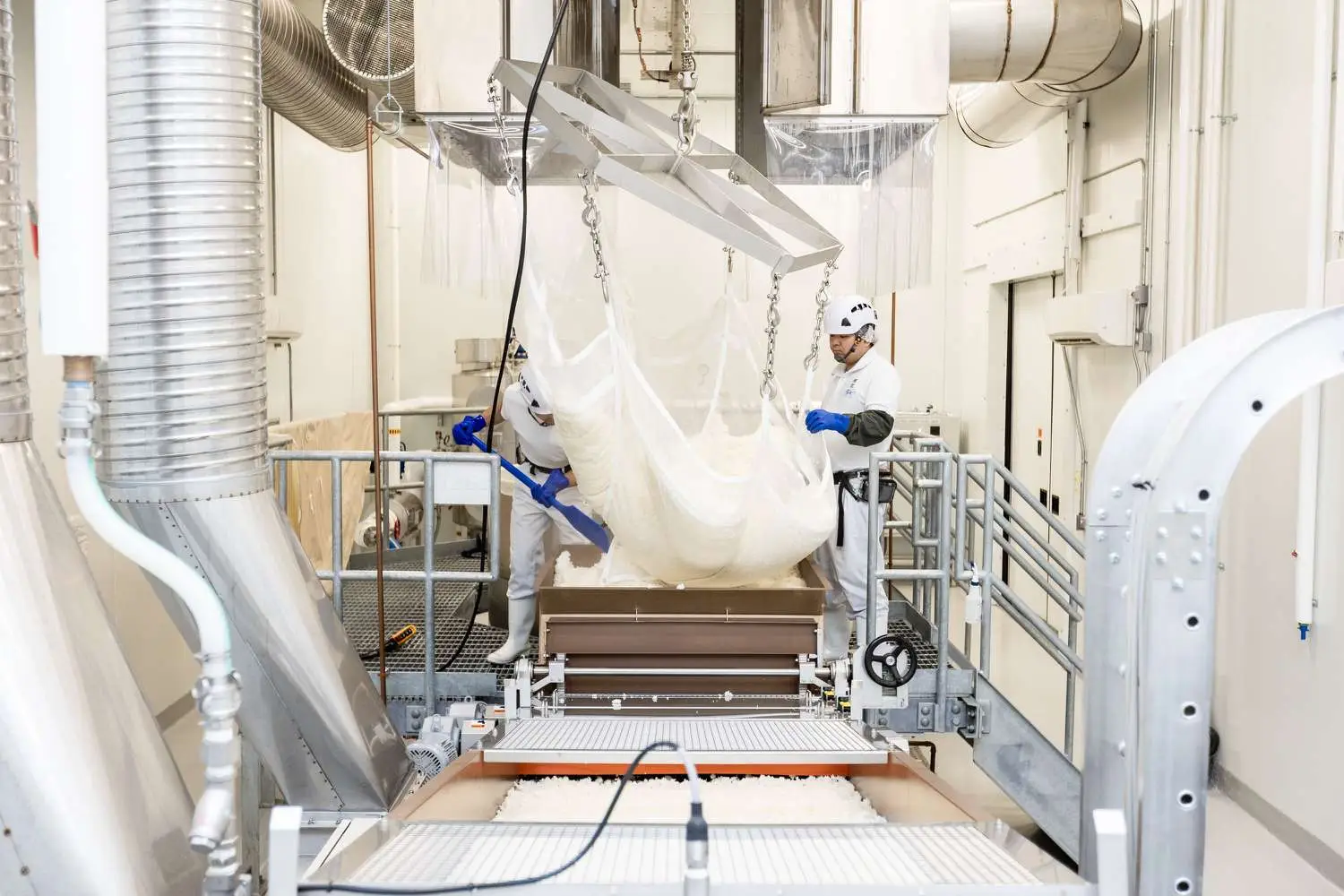 Production of sake by two workers in helmets, white outfits and gloves, at Dassai Blue Brewery