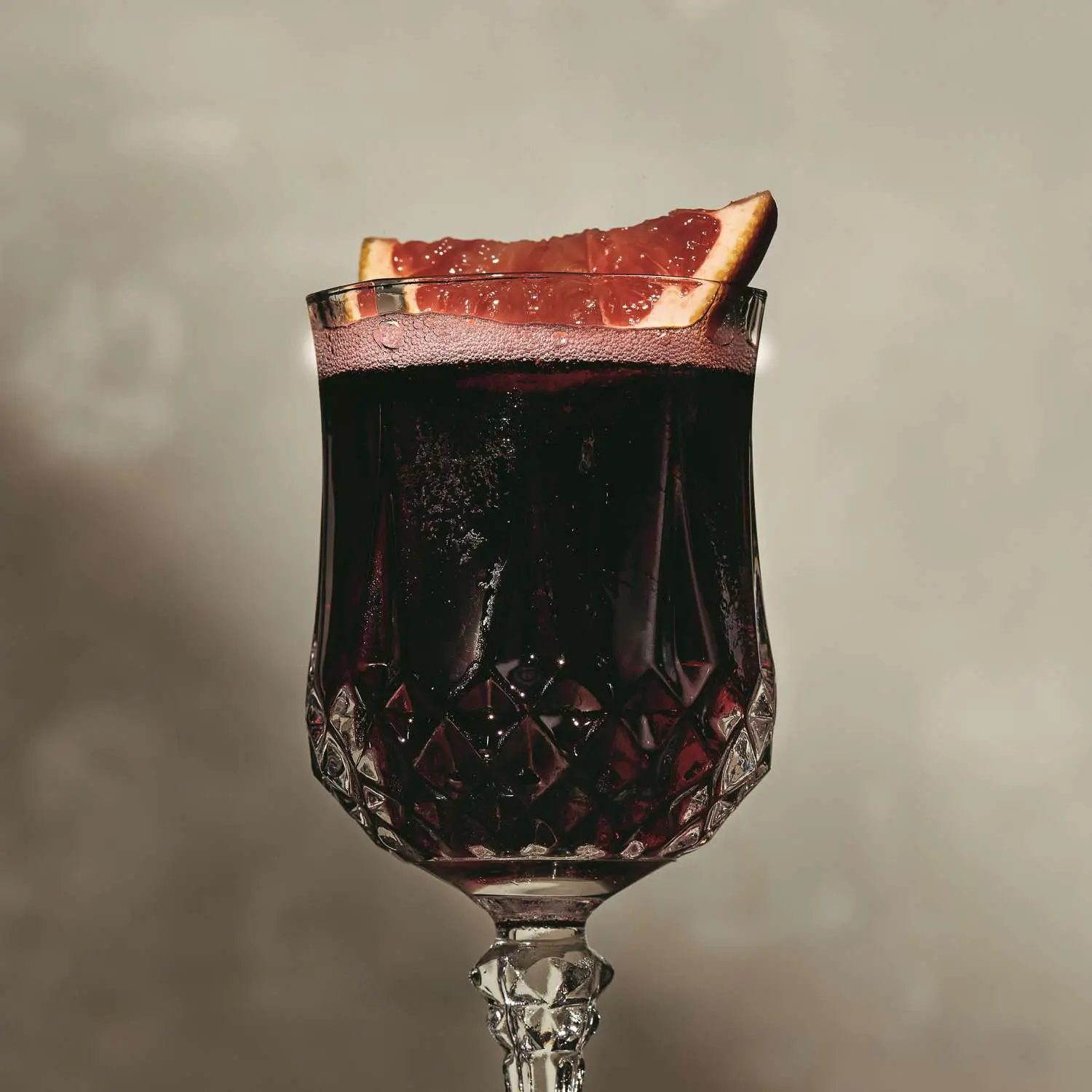 Claret Cup cocktail in an ornate retro wine glass with grapefruit slice garnish