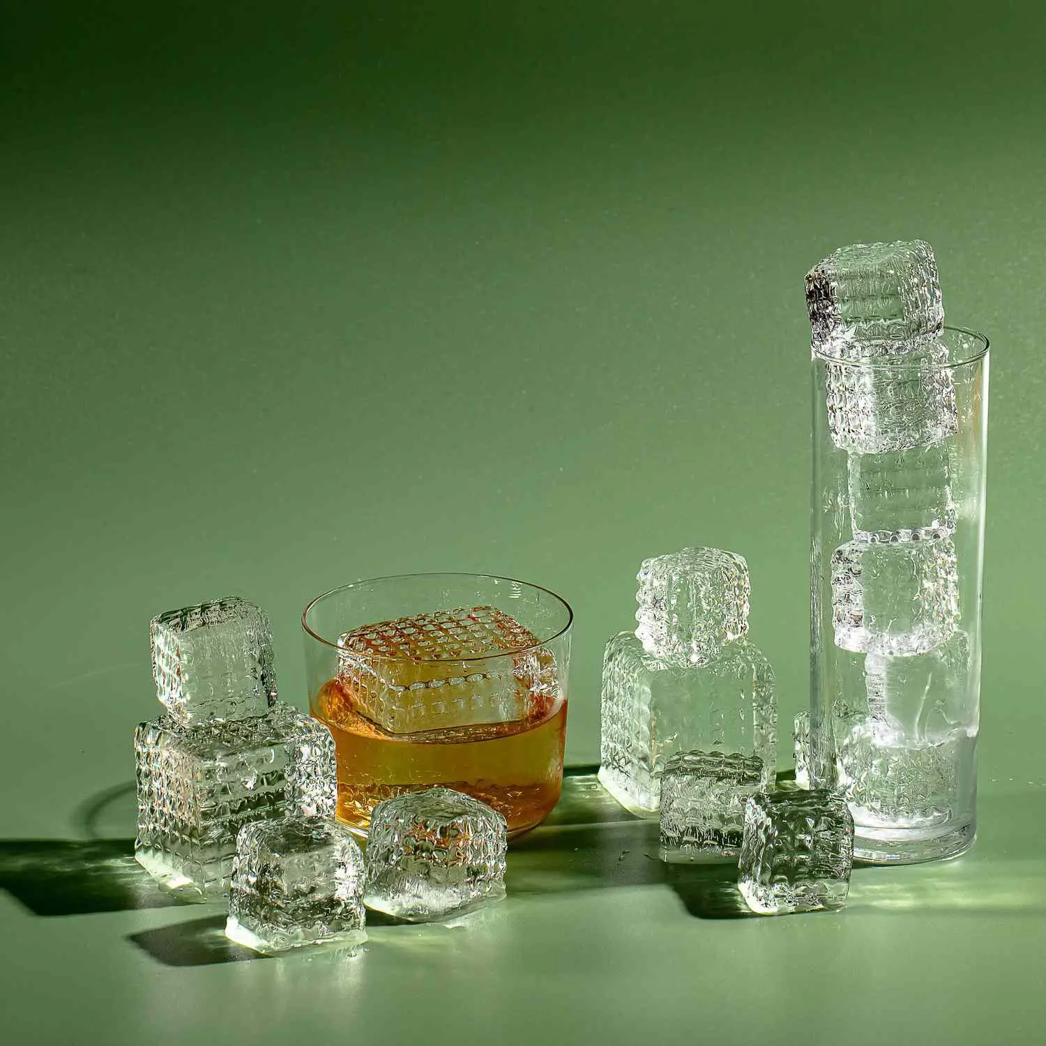 Stacks of perfectly clear ice in rocks glass and Collins glass, with shapes embedded