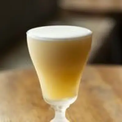 Stone Fruit Sour in footed Irish Coffee glass with thick layer of egg white foam on top