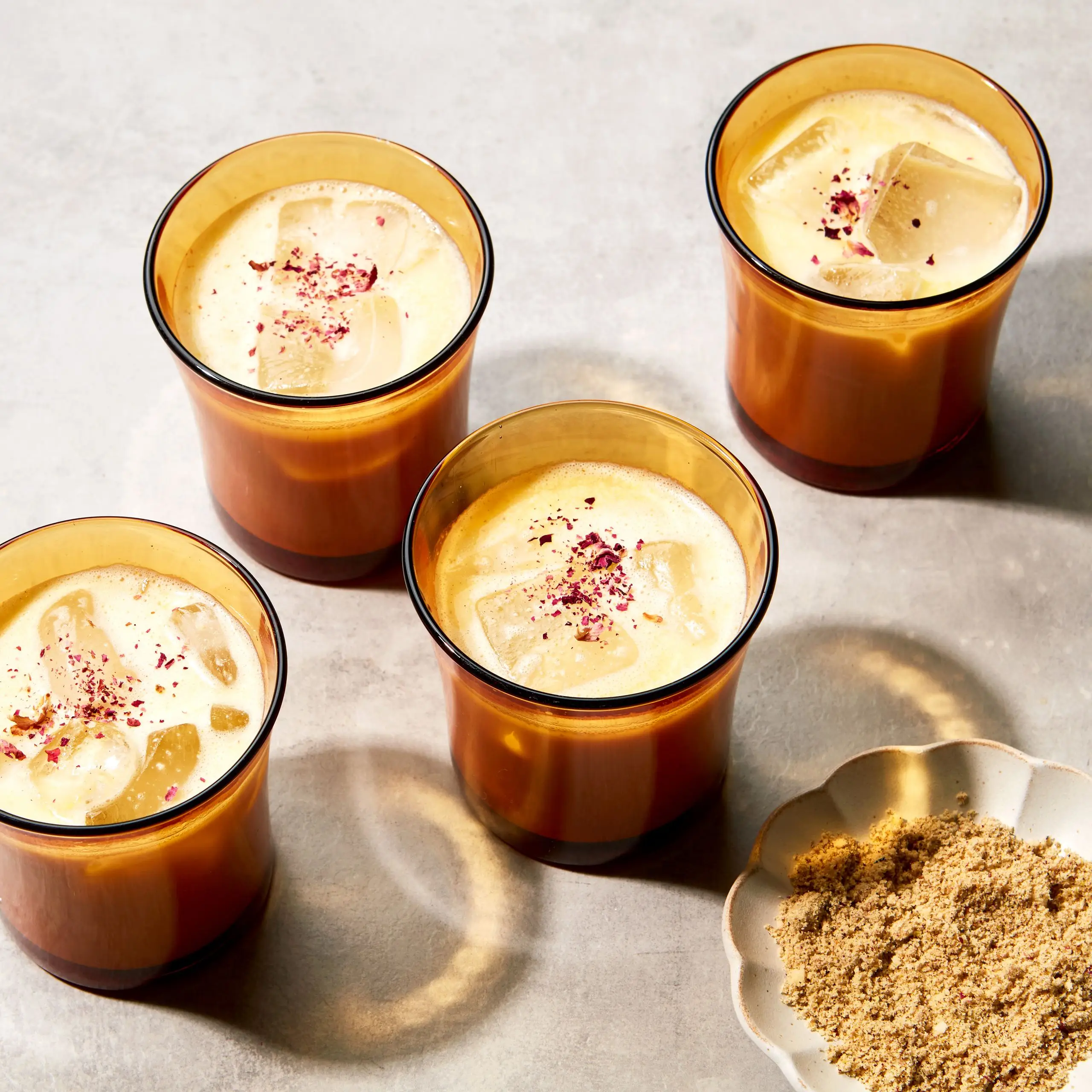 Glasses of a milk based drink spiced with thandai masala garnished with rose petals.