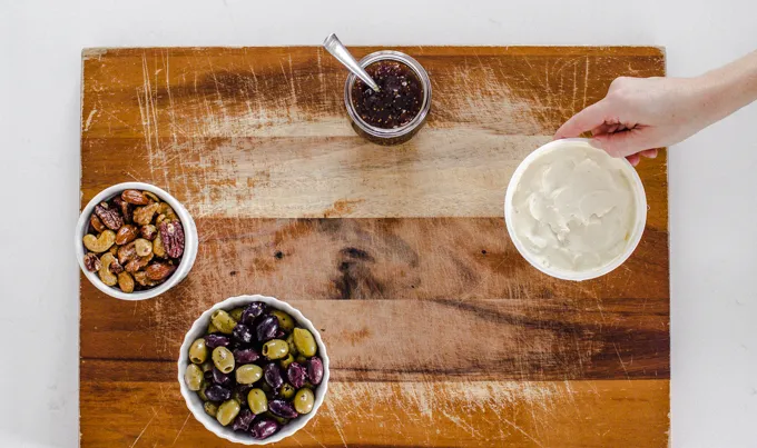 Arranging containers of snacks on a wooden cutting board.' title='Easy Snack Board Ideas