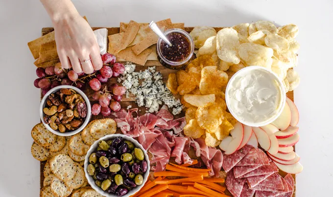 Adding the grapes carrots and apples to the snack board.' title='Easy Snack Board Ideas