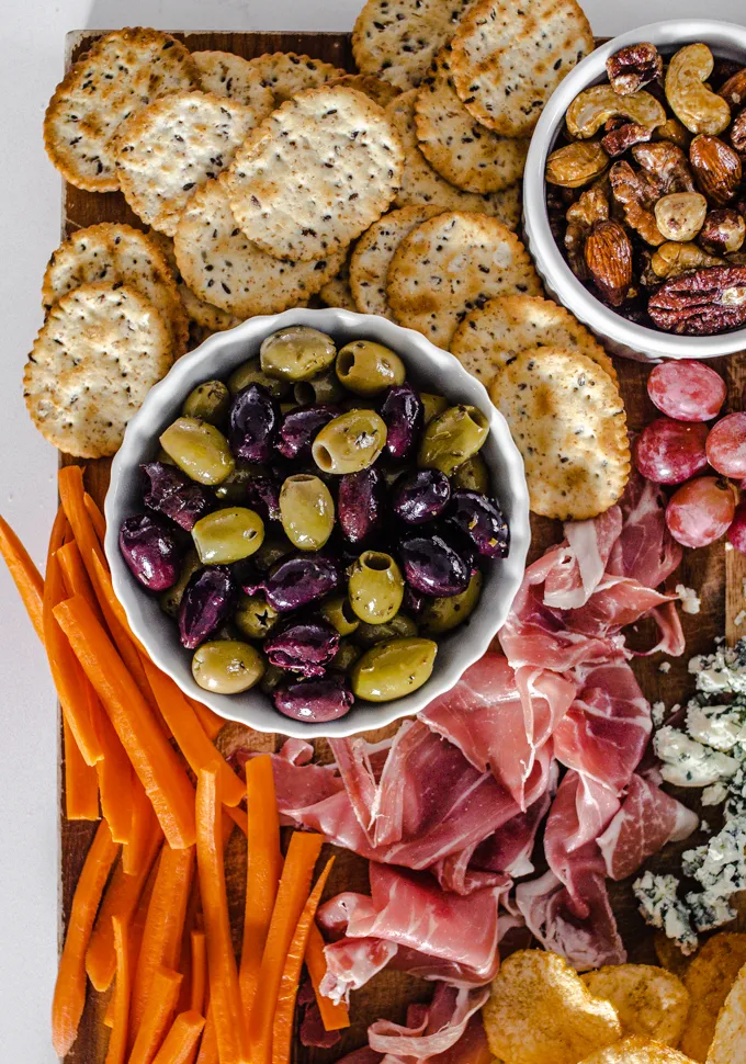 Olives crackers roasted nuts grapes prosciutto blue cheese chips and carrots.' title='Easy Snack Board Ideas