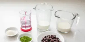 All of the ingredients needed to make an iced matcha coffee laid out on a white countertop.' title='Matcha Coffee Recipe