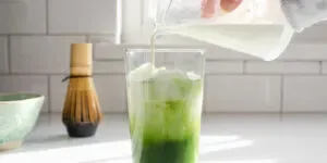 Pouring the milk and cream on top of the matcha and ice cubes.' title='Matcha Coffee Recipe