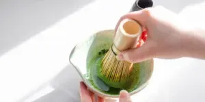 Using a bamboo matcha whisk (AKA chasen) to whisk the matcha with the water and sugar until smooth.' title='Matcha Coffee Recipe