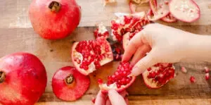 A pomegranate broken into sections on a wooden cutting board.' title='How to Remove Seeds from a Pomegranate