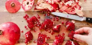 Sections of peeled pomegranate on a wooden cutting board.' title='How to Remove Seeds from a Pomegranate