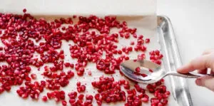 Placing pomegranate seeds on a parchment lined baking sheet to freeze.' title='How to Remove Seeds from a Pomegranate