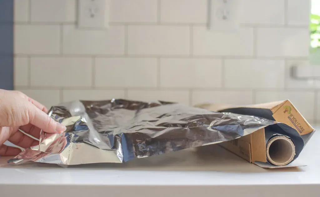 Pulling out a sheet of aluminum foil to use as a parchment paper substitute for baking.' title='Parchment Paper Substitute for Baking