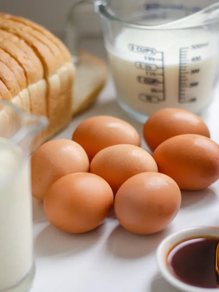 7 brown eggs on a white countertop with other ingredients around them.' title='Apple French Toast Casserole Recipe