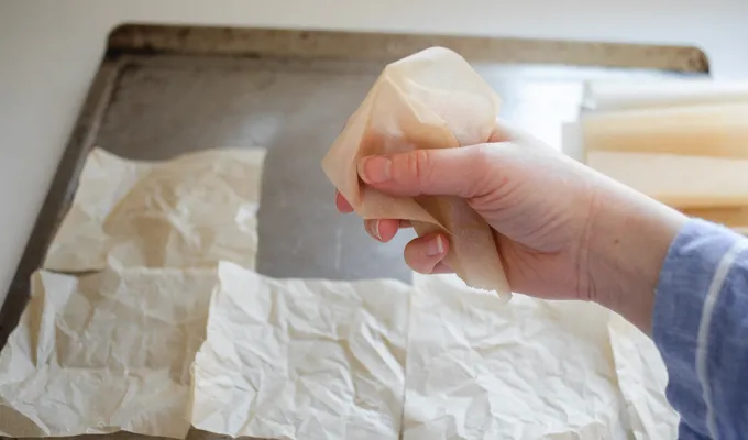 Crinkling parchment paper to make it lay flat.' title='Sourdough English Muffins