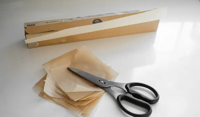 Cutting out squares of parchment paper for sourdough English muffins.' title='Sourdough English Muffins