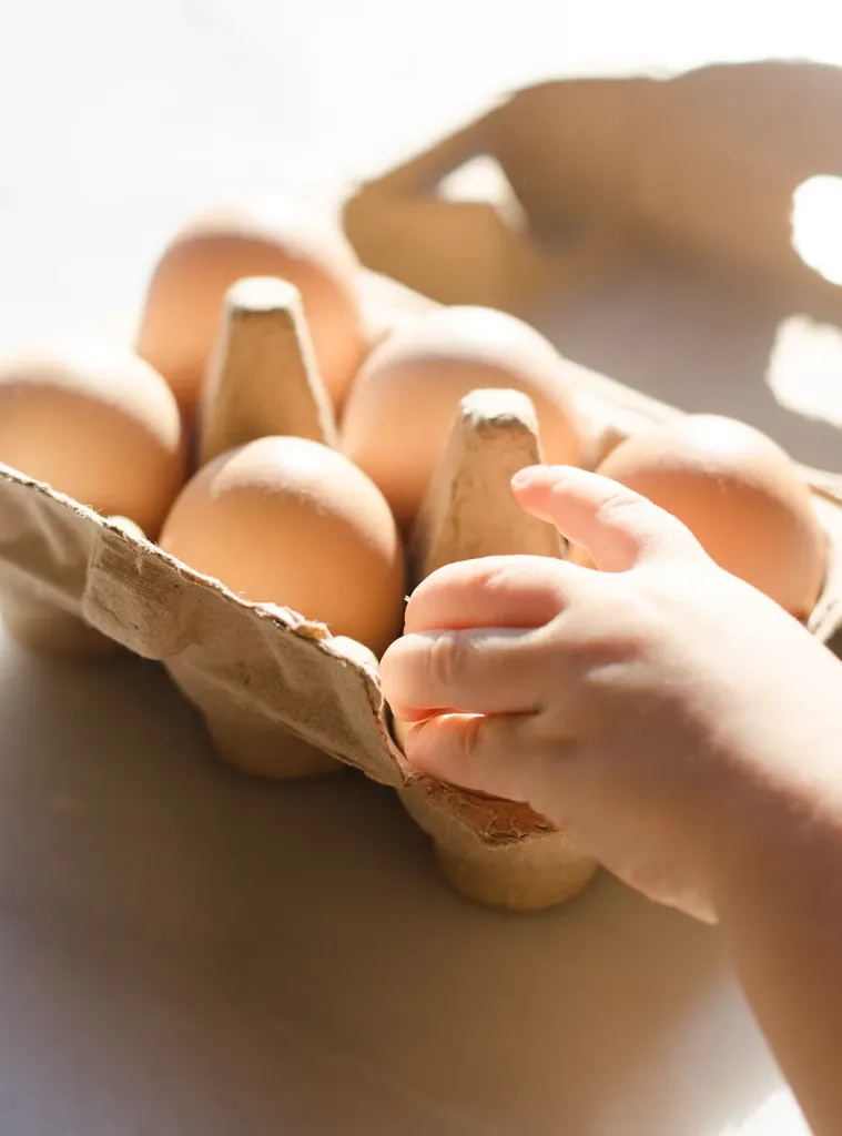 A little hand taking an egg out of a carton. ' title='Savory Dutch Baby Puff Pancake