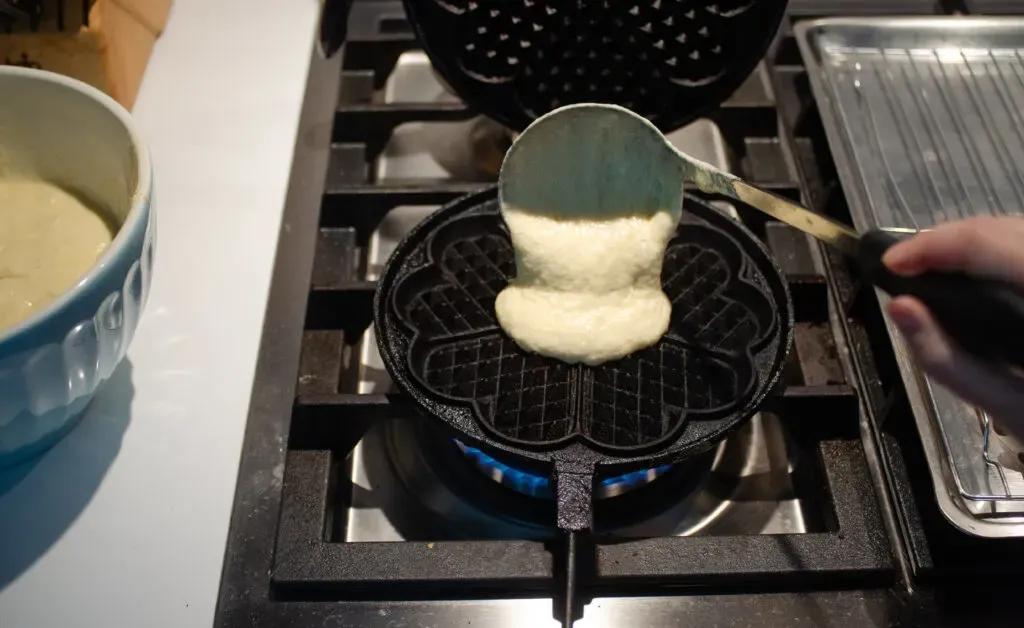 Using a ladle to transfer the waffle batter to the hot iron.' title='Sourdough Discard Waffles Recipe