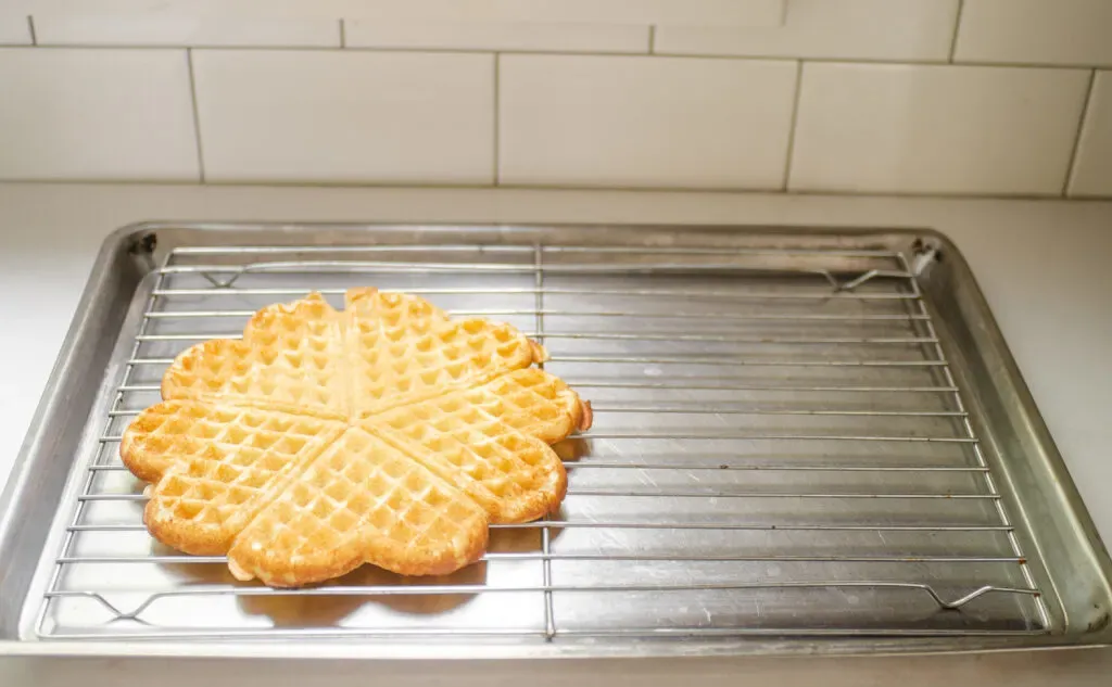 Placing a cooked sourdough discard waffle on a wire cooling rack on a baking tray. ' title='Sourdough Discard Waffles Recipe