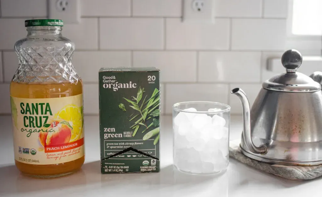All of the ingredients needed to make a peach green tea lemonade (Starbucks Copycat) laid out on a white counter.' title='Starbucks Peach Green Tea Lemonade Recipe