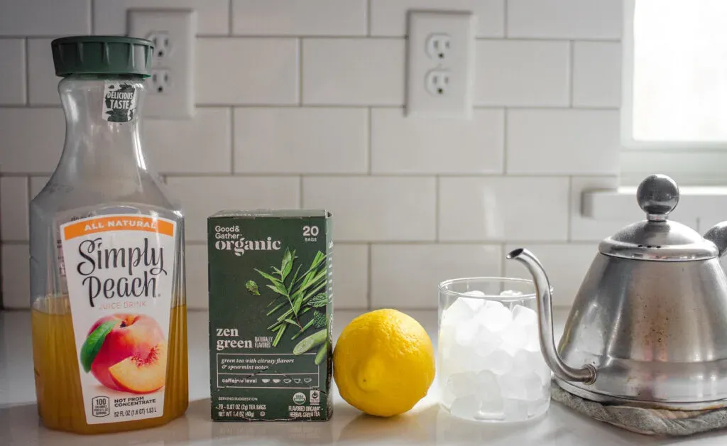 All of the ingredients needed to make a Starbucks Peach Green Tea Lemonade at home laid out on a white countertop.' title='Starbucks Peach Green Tea Lemonade Recipe