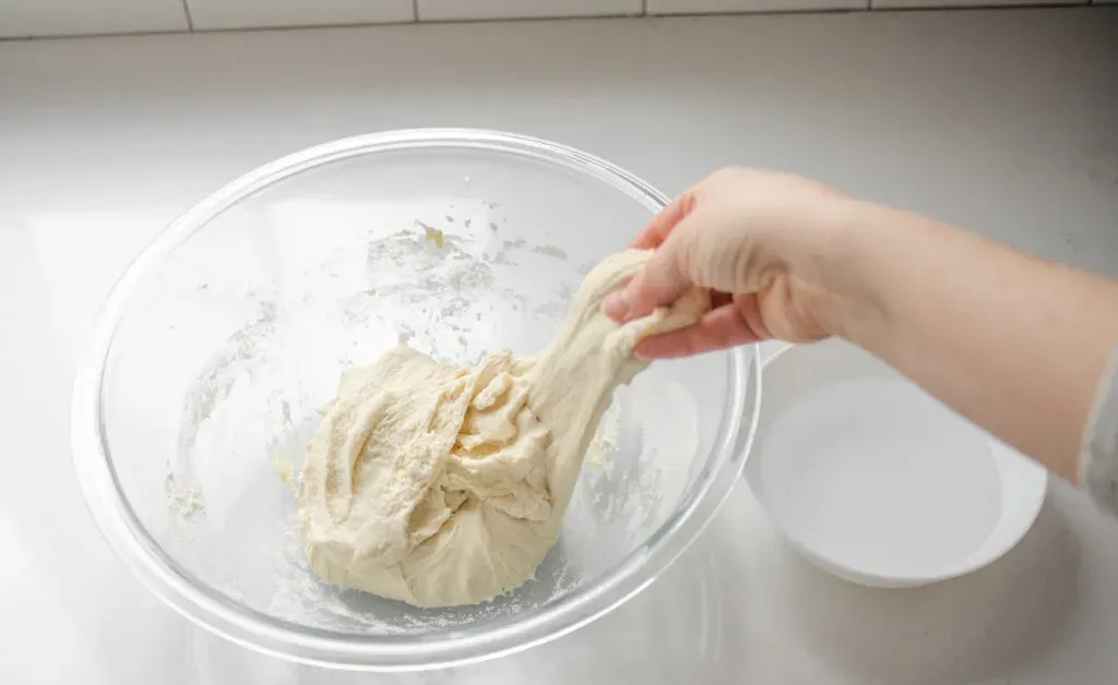 Performing the first stretch and fold sequence to develop the gluten in the sourdough pizza crust. ' title='Sourdough Pizza Crust Recipe