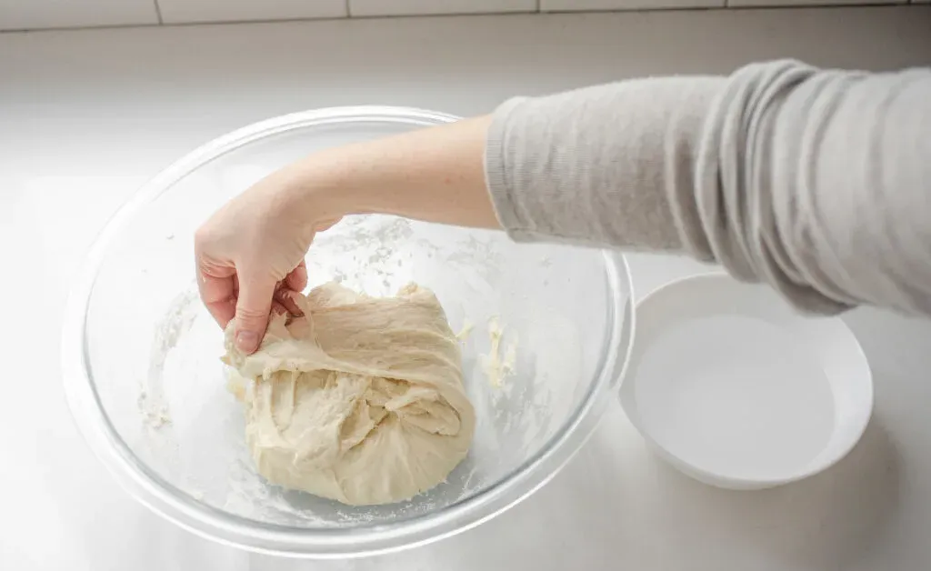 Performing the first stretch and fold sequence to develop the gluten in the sourdough pizza crust. ' title='Sourdough Pizza Crust Recipe