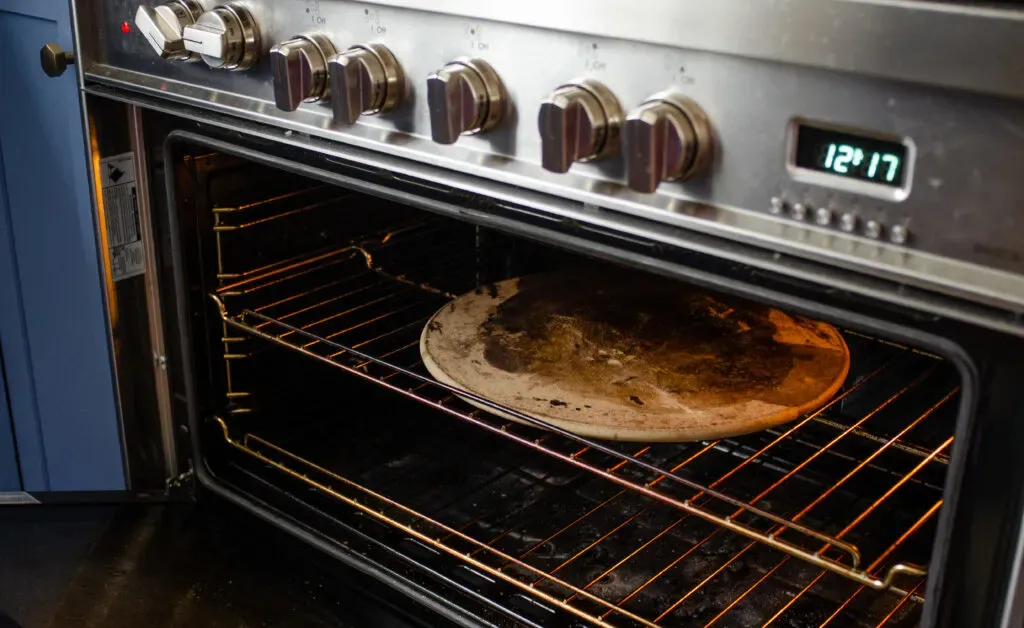 Placing a pizza stone in an oven to preheat for baking the sourdough pizza crust. ' title='Sourdough Pizza Crust Recipe