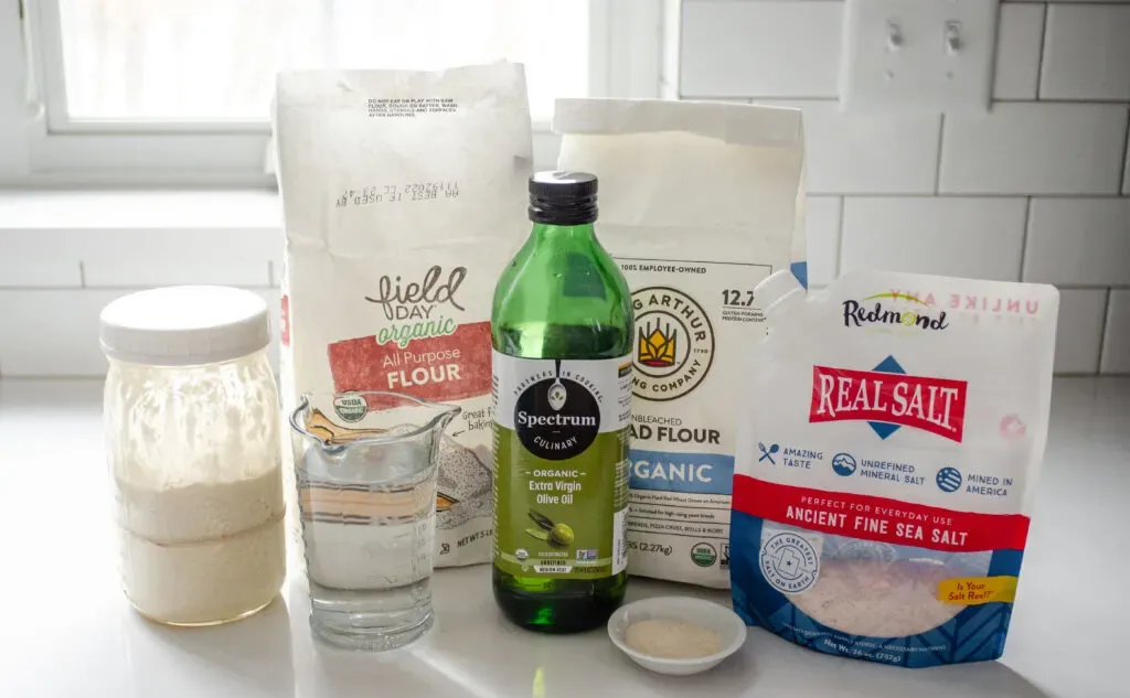 All of the ingredients needed to make a sourdough pizza crust without yeast on a white countertop.' title='Sourdough Pizza Crust Recipe