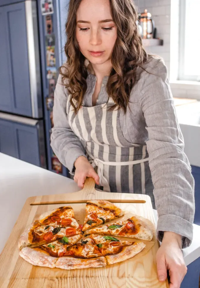 Removing the cooked sourdough pizza from the oven onto a cutting board.' title='Sourdough Pizza Crust Recipe