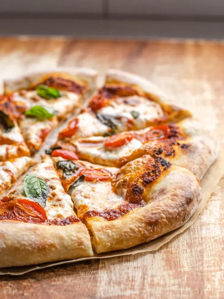 Pizza with a sourdough crust on a wooden cutting board cut into pieces. ' title='Sourdough Pizza Crust Recipe