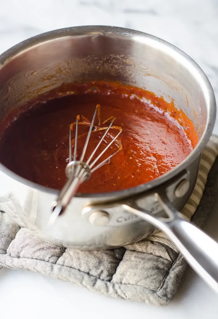 Homemade pizza sauce in a small saucepan with a whisk in it. ' title='Easy Homemade Pizza Sauce with Tomato Paste