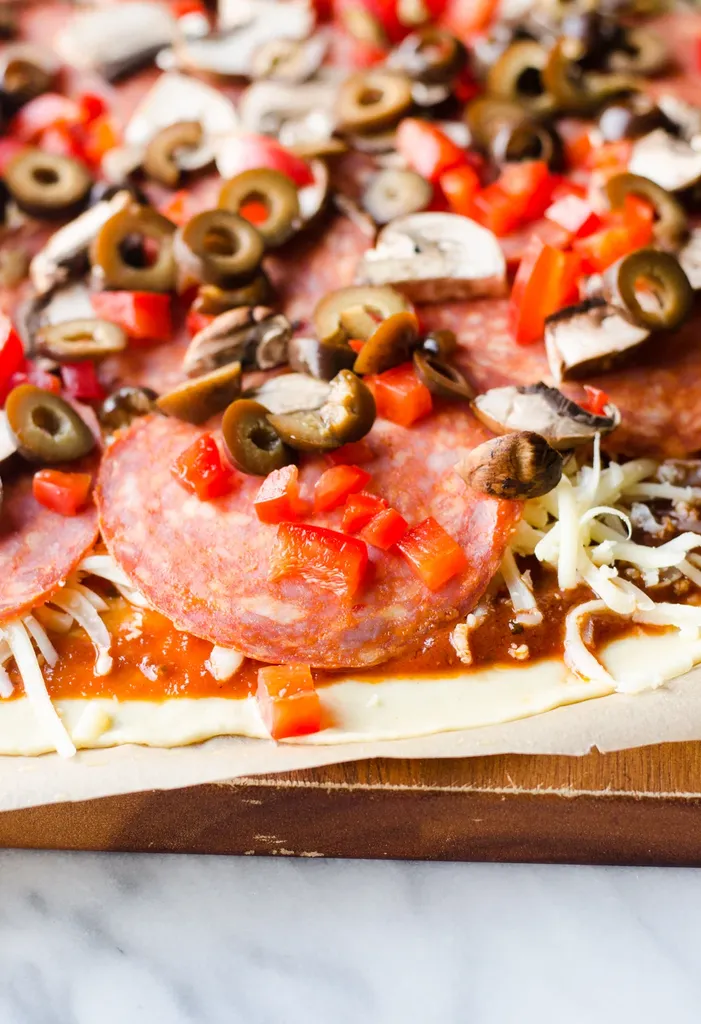 Homemade pizza on a wooden cutting board waiting to be baked!' title='Easy Homemade Pizza Sauce with Tomato Paste