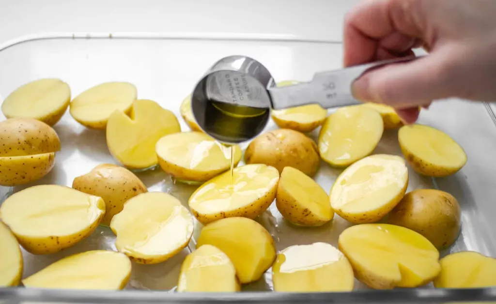 Pouring the EVOO over the little Yukon gold potatoes. ' title='Roasted Little Potato Recipe