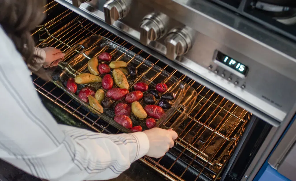 Placing the pan of mini potatoes in the oven to roast.' title='Roasted Little Potato Recipe
