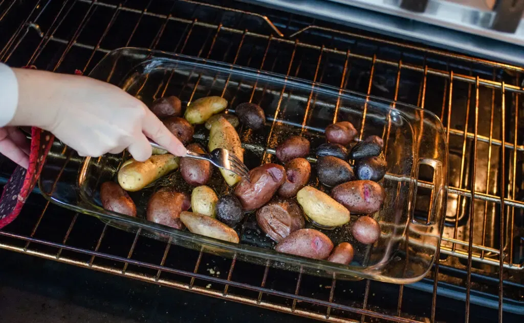 Testing the baby potatoes for doneness with a fork.' title='Roasted Little Potato Recipe