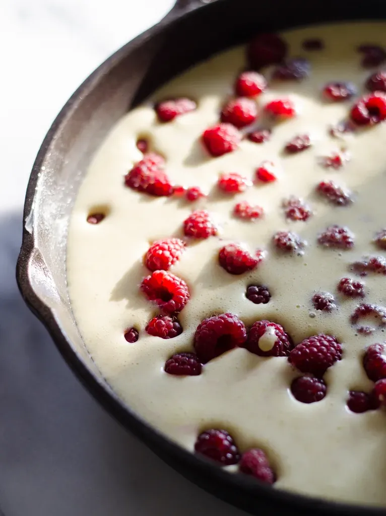 The batter poured over the berries in the pan.' title='Raspberry Clafoutis