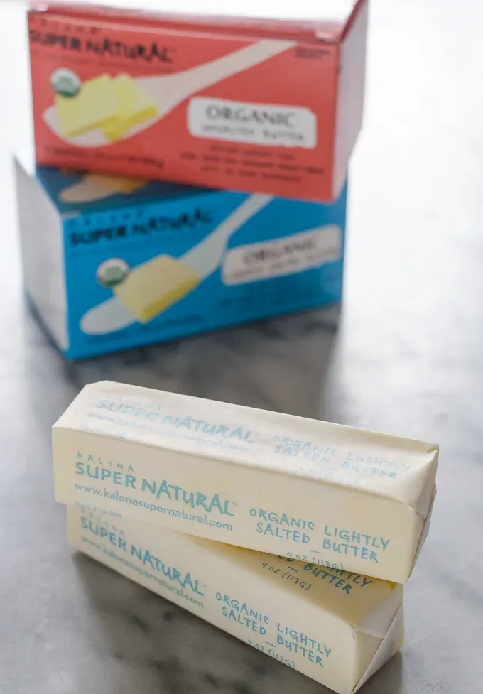 Sticks of Kalona SuperNatural butter on a marble surface with packaging in the background.' title='Ingredient Spotlight: Kalona SuperNatural Butter
