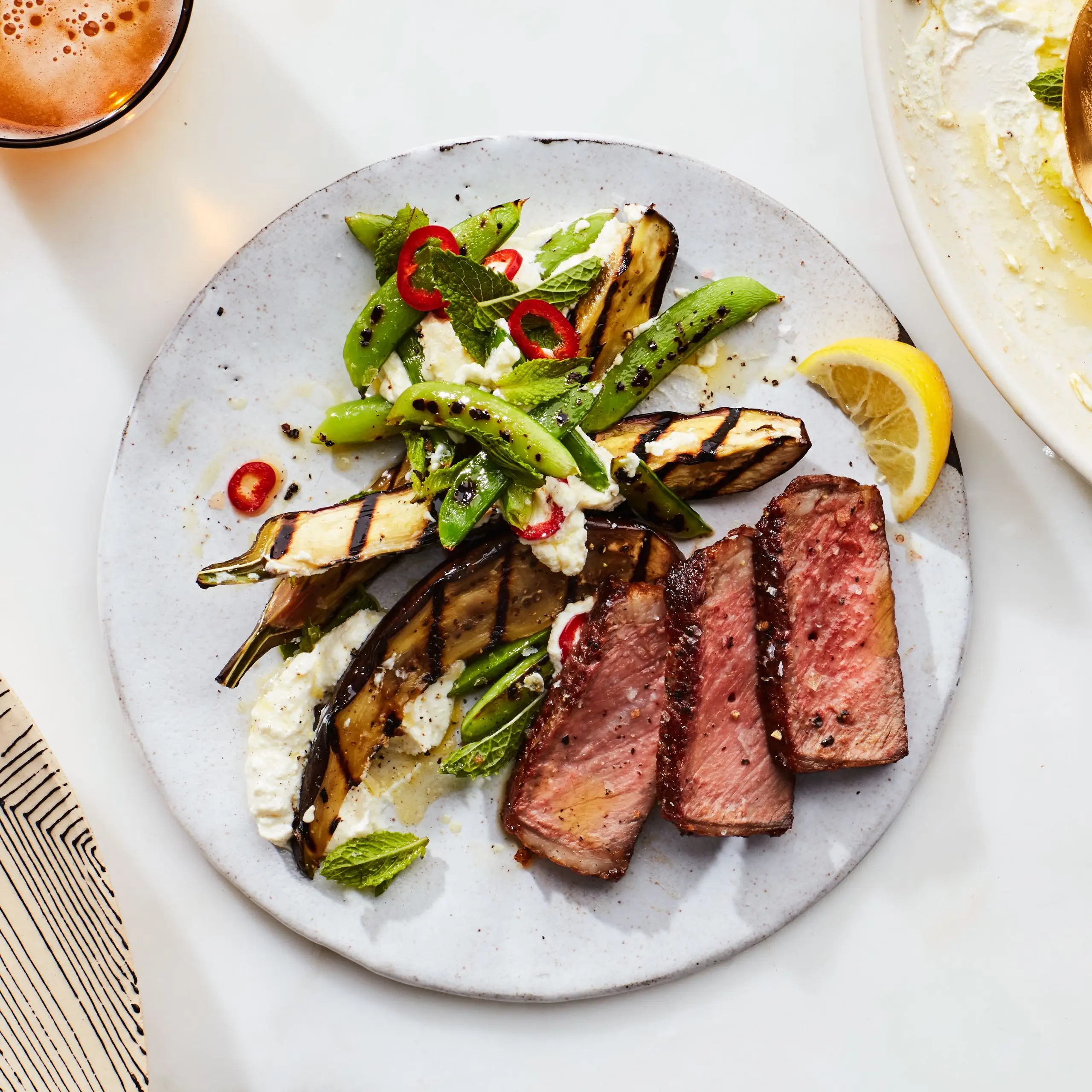Bife grelhado com ervilhas e berinjela sobre ricota chicoteada