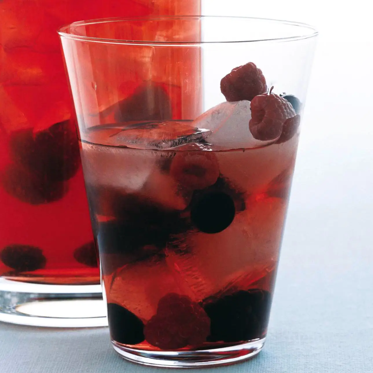 Pitcher and glass of rose sangria with berries.