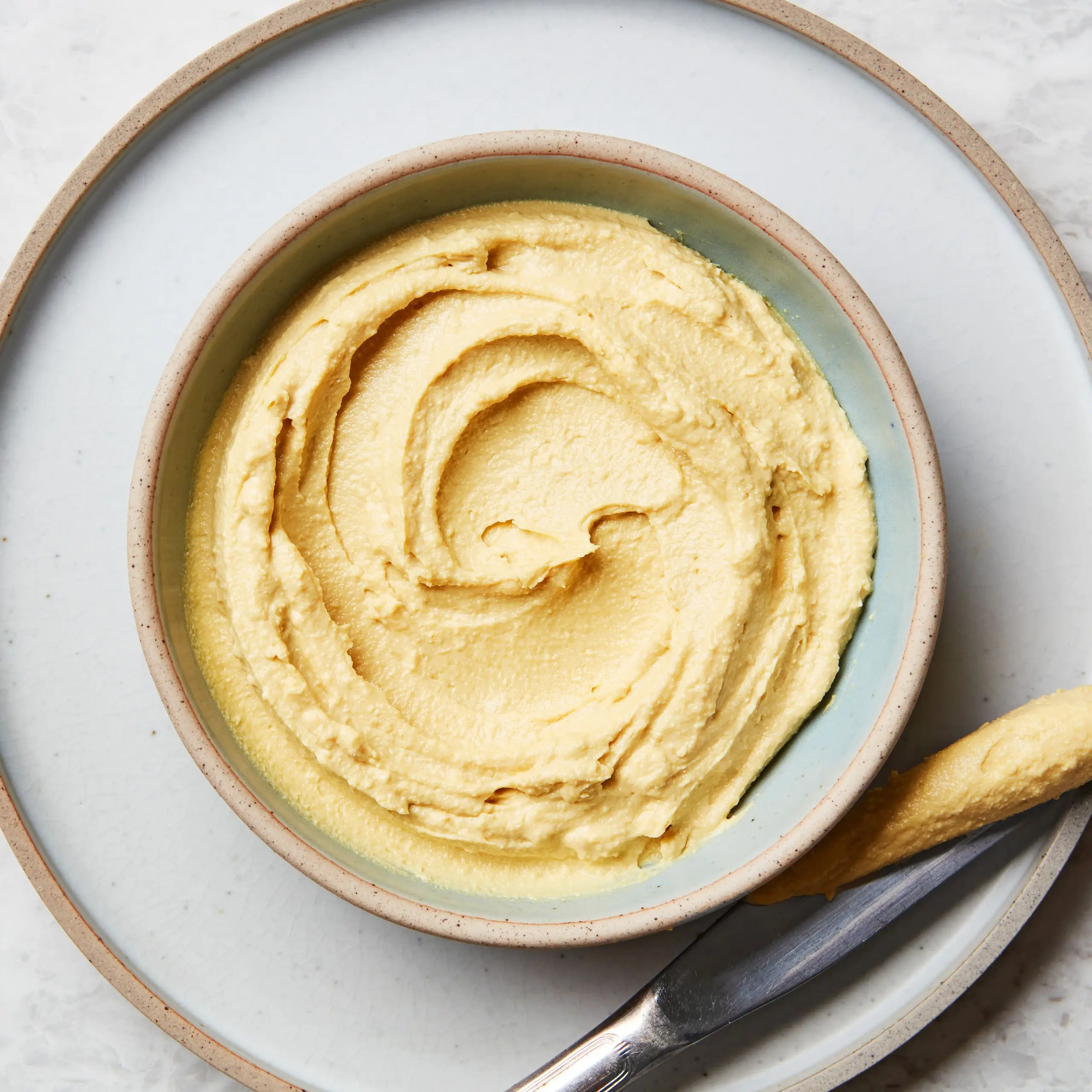 A bowl of vegan beer cheese with a butter knife.