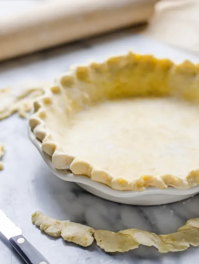 Sourdough Pie Crust in a pie pan with the crust trimmings around it.' title='Sourdough Pie Crust
