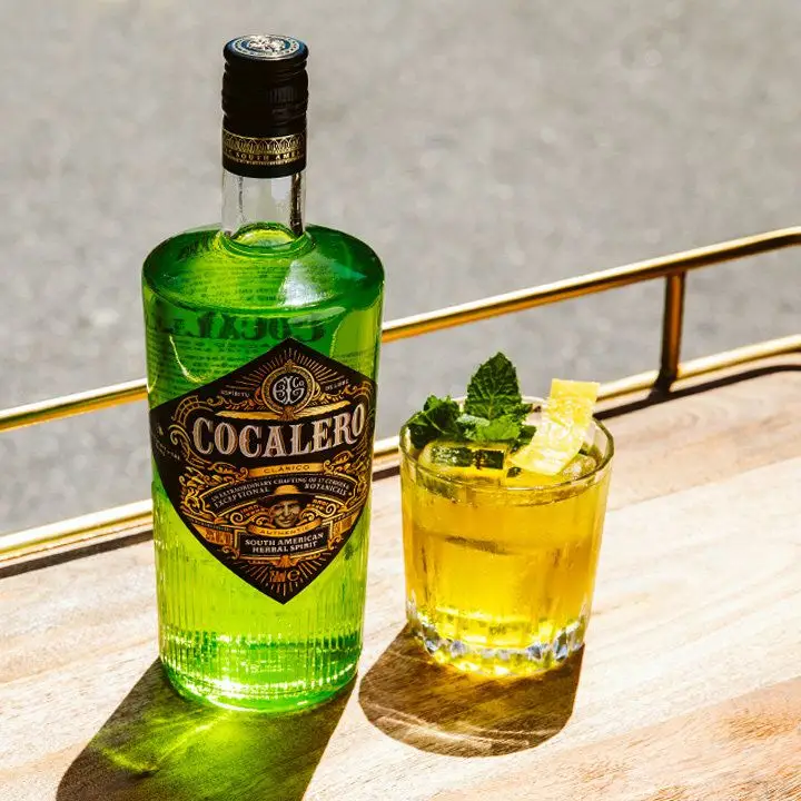 Cocalero Clásico Herbal Spirit Vodka bottle on a tray next to a cocktail