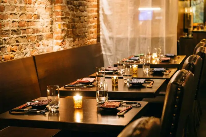 A neat row of four two-top banquette tables against an exposed brick wall
