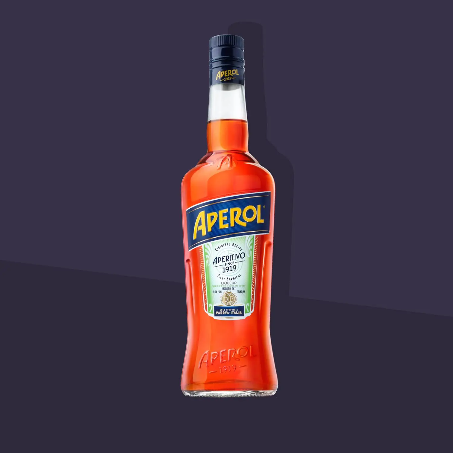 A bottle of Aperol red bitter liqueur overtop a purple background