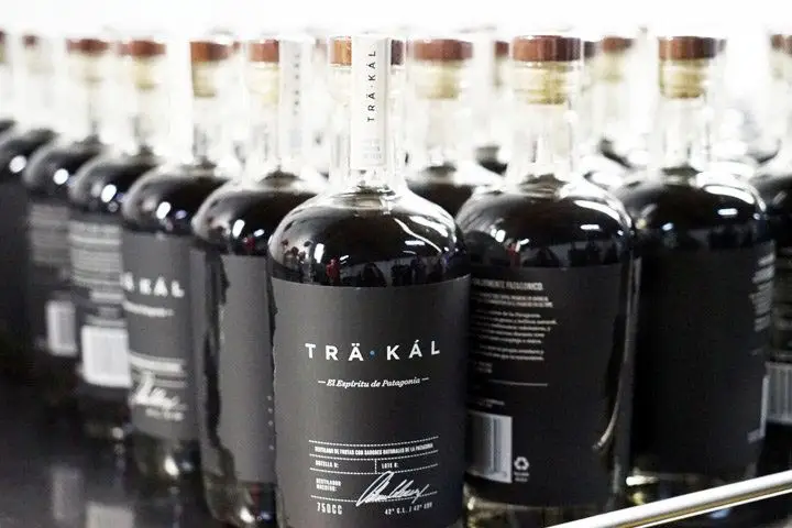 A metal shelf full of clear Trakal bottles with black and white labels and a dark-hued liquid inside