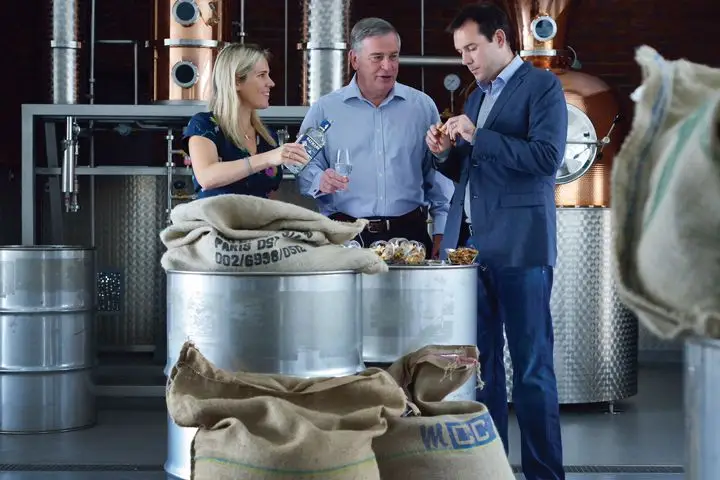 One woman and two men tasting gin inside a distillery