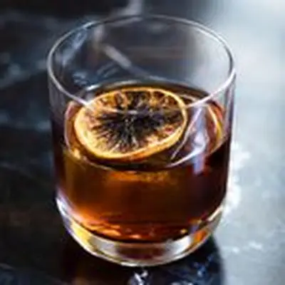 Black Negroni cocktail with flamed orange wheel