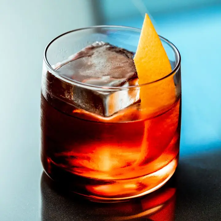 Boulevardier cocktail with square ice cube and orange peel served in rocks glass