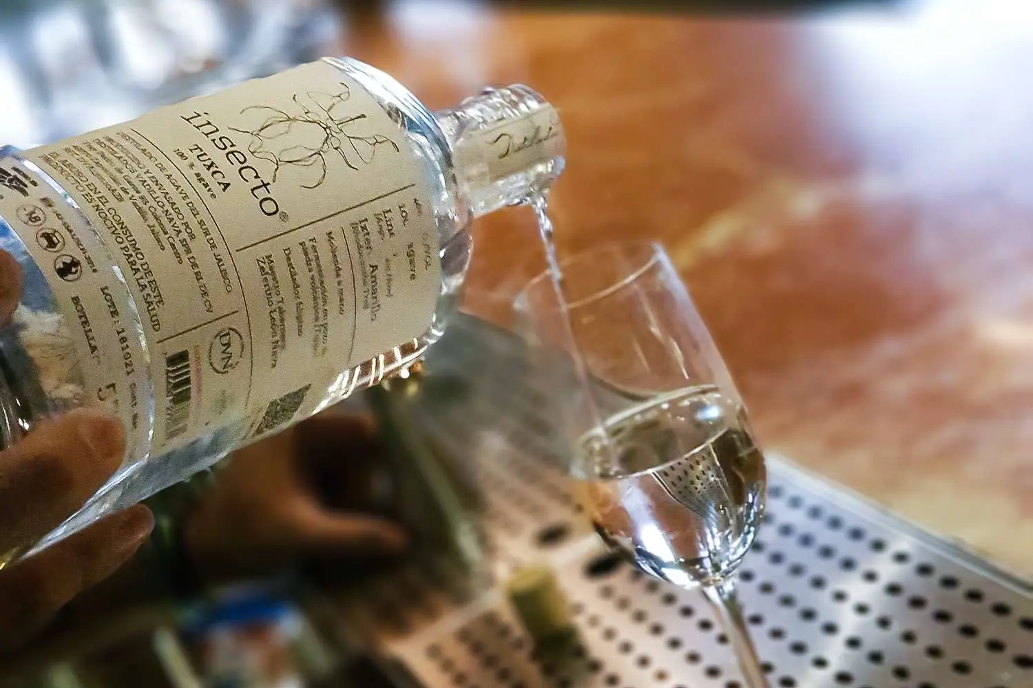 Insecto Tuxca being poured into glass on bar top