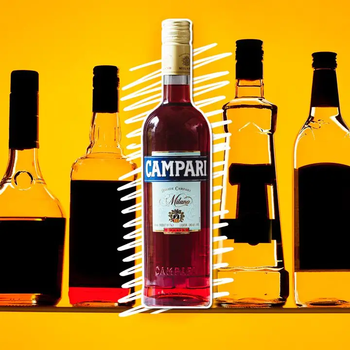A bottle of ruby-hued Campari sits on a golden background. It is surrounded by other bottles, though their labels are darkened so as to be unreadable